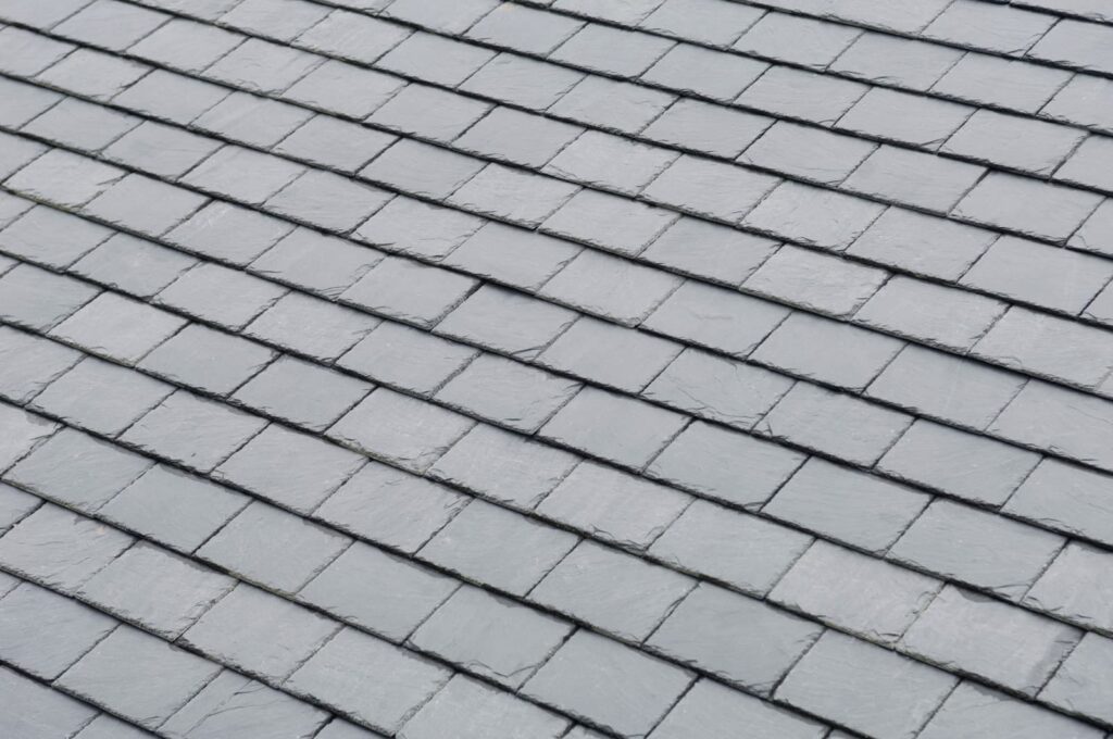 Close-up view of a grey slate tile roof, showing neatly arranged overlapping rectangular tiles, expertly installed by our professional roofing contractor.