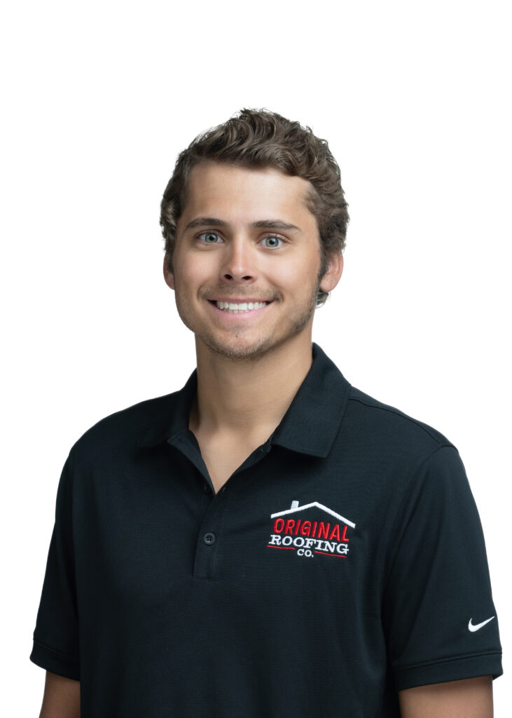 A man with curly hair, wearing a black polo shirt with the "Original Roofing Co." logo, smiles at the camera. As a dedicated roofing contractor, he takes pride in providing top-notch roofing services to the community.