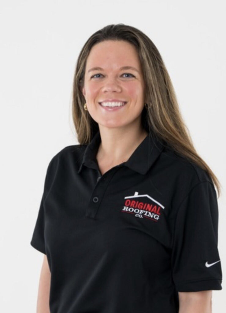 A woman wearing a black polo shirt with the logo "Original Roofing Co." smiles while standing against a plain white background, representing top-notch roofing services.